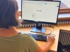 Eine Person sitzt vor einem Computer in der Mediathek.