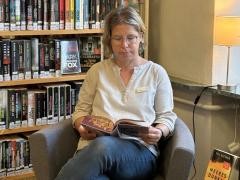 Eine Person sitzt in einer Leseecke und liest ein Buch.