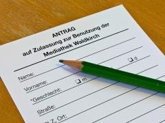 Auf einem Tisch liegen ein Anmeldeformular und ein Stift.