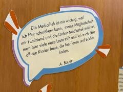 An einer Holzwand in der Mediathek klebt ein ausgedrucktes Zitat.