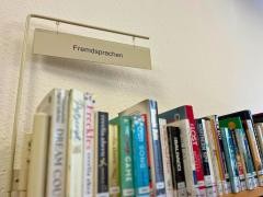 Auf einem Schild steht Fremdsprachen. Unter dem Schild stehen Bücher.