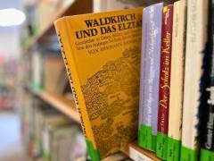 In einem Regal stehen verschiedene Bücher. Ein gelbes Buch ist aus dem Regal gezogen. Auf dem Buch steht "Waldkirch und das Elztal".