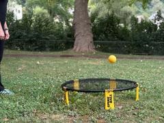 Eine Person spielt in einem Park Spikeball.