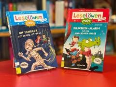 Zwei Bücher stehen auf einem roten Tisch.