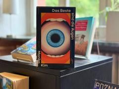 Das Buch "Das Beste sind die Augen" steht auf einem schwarzen Regal. Im Hintergrund sind nur vershwommen weitere Bücher erkennbar.