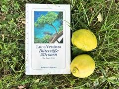 Der Krimi "Bittersüße Zitronen" liegt in einem Rasen. Daneben liegen zwei Zitronen.